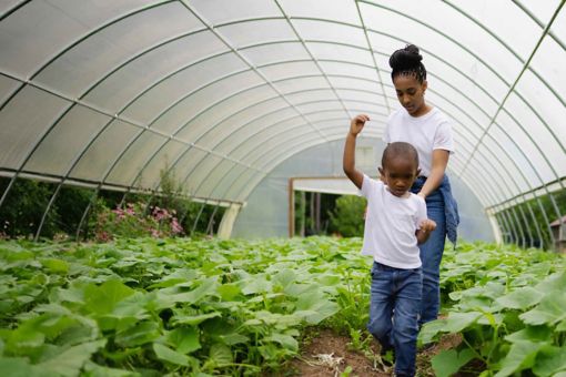 A woman and a young boy walking through a greenhouse